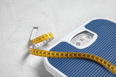 Photo of Scales and measuring tape on light background with space for text. Weight loss