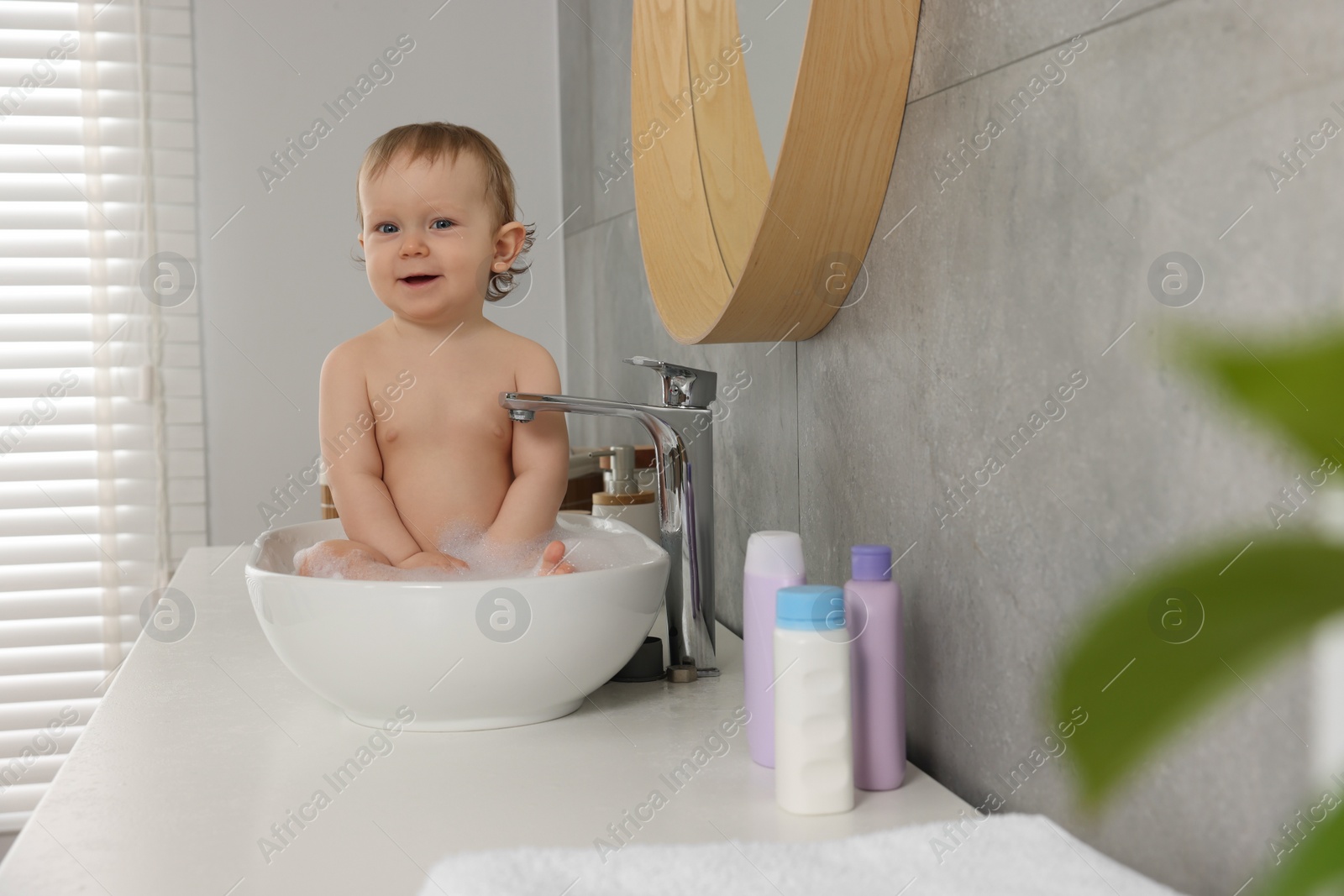 Photo of Cute little baby bathing in sink at home