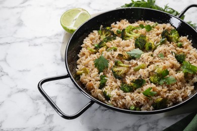 Photo of Tasty fried rice with vegetables served on white marble table, closeup. Space for text