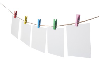 Photo of Clothespins with empty notepapers on string against white background. Space for text