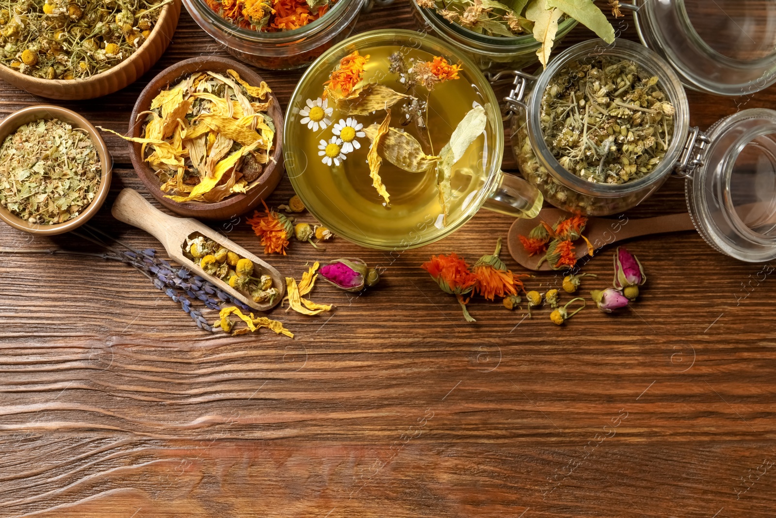 Photo of Freshly brewed tea and dried herbs on wooden table, flat lay. Space for text