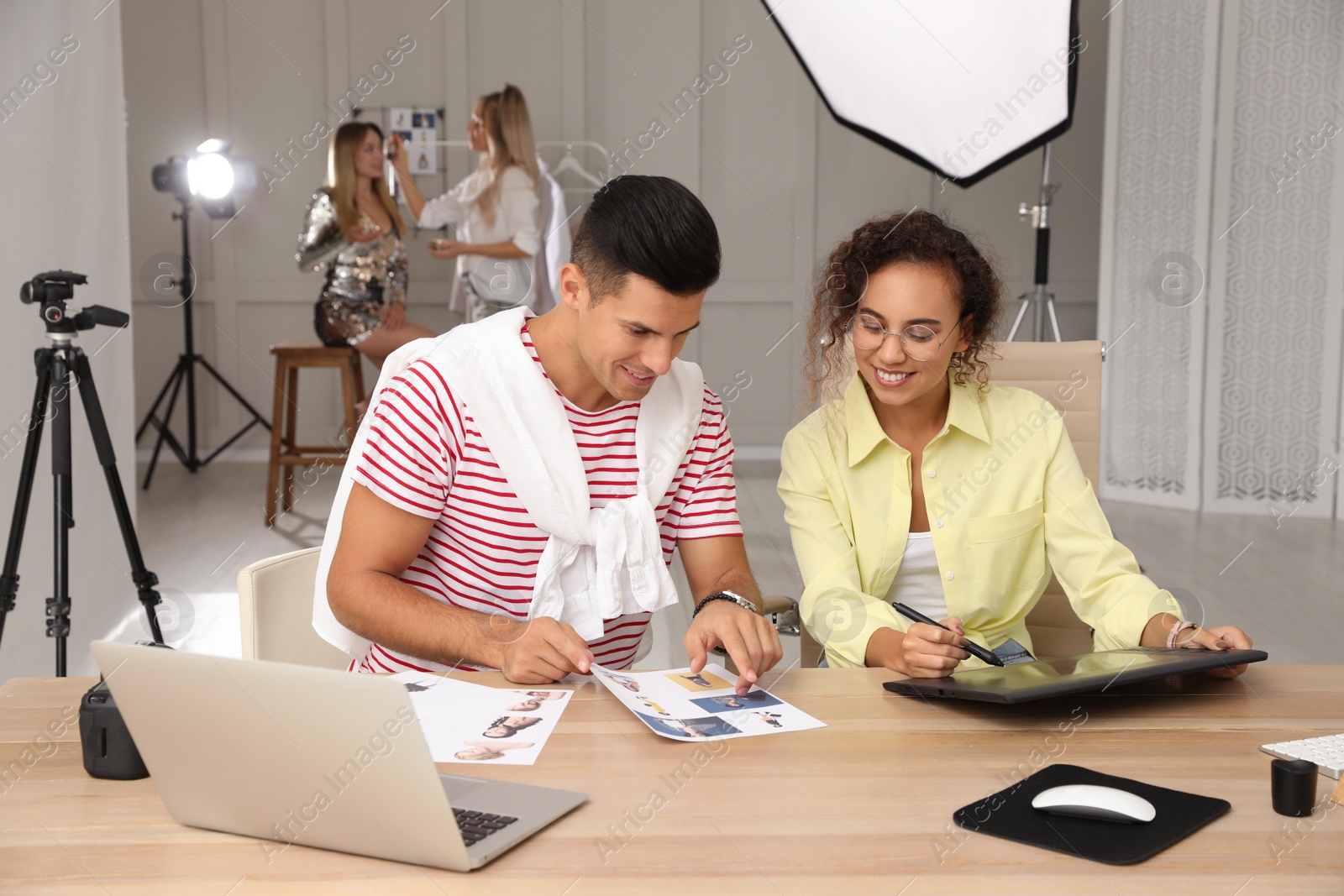 Photo of Professional retoucher with colleague working at desk in photo studio