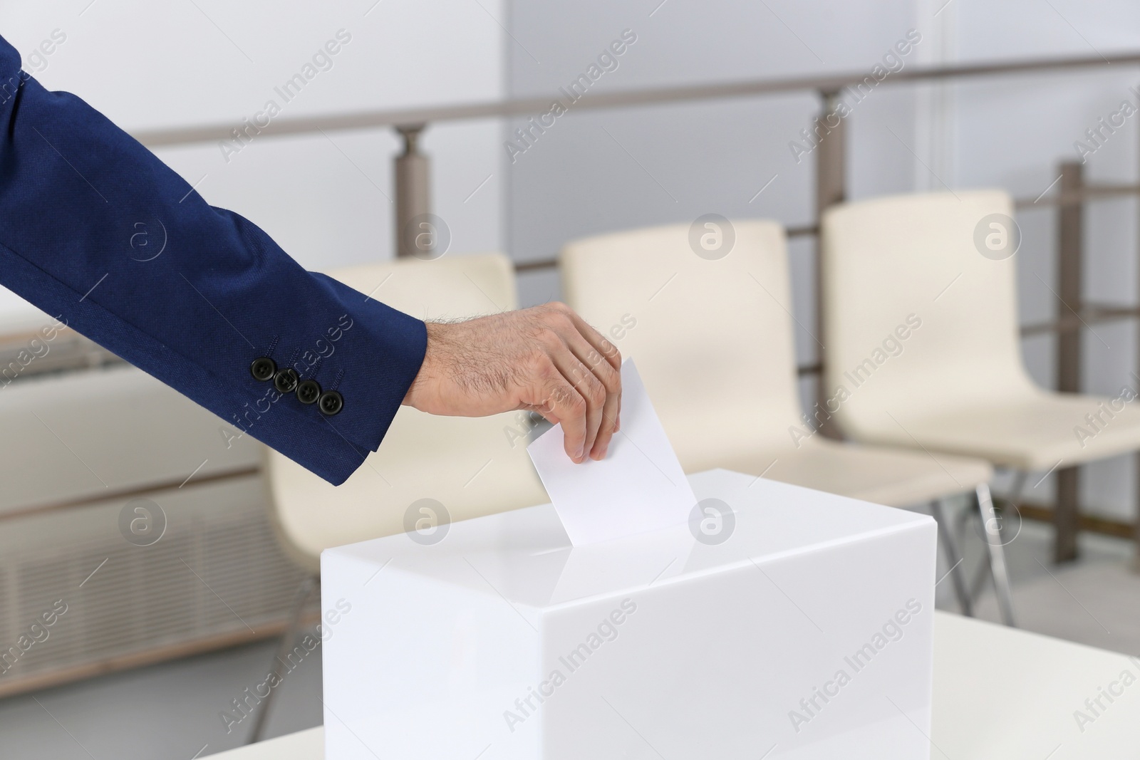 Photo of Man putting his vote into ballot box at polling station, closeup