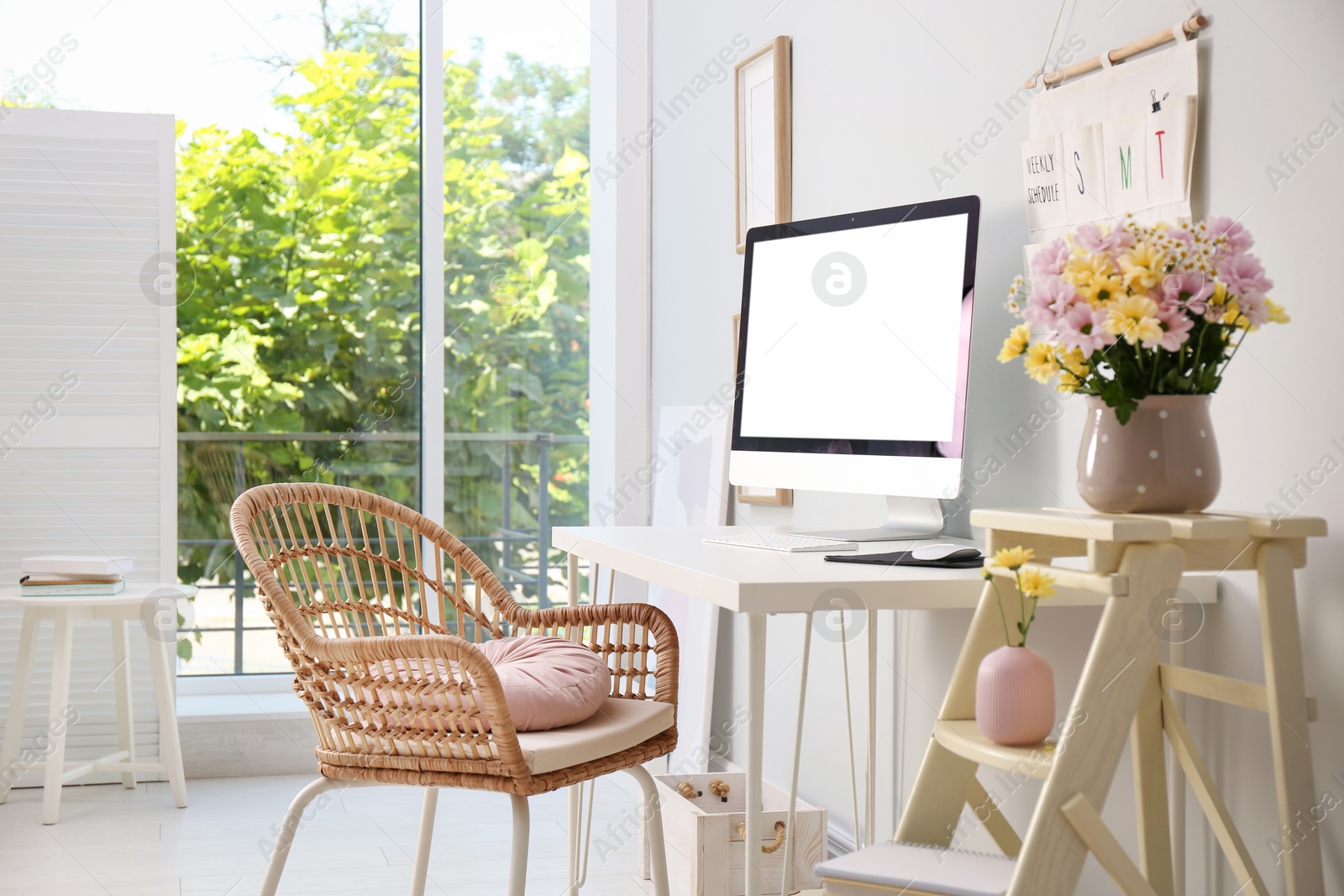 Photo of Comfortable workplace with modern computer and flowers in room. Interior design