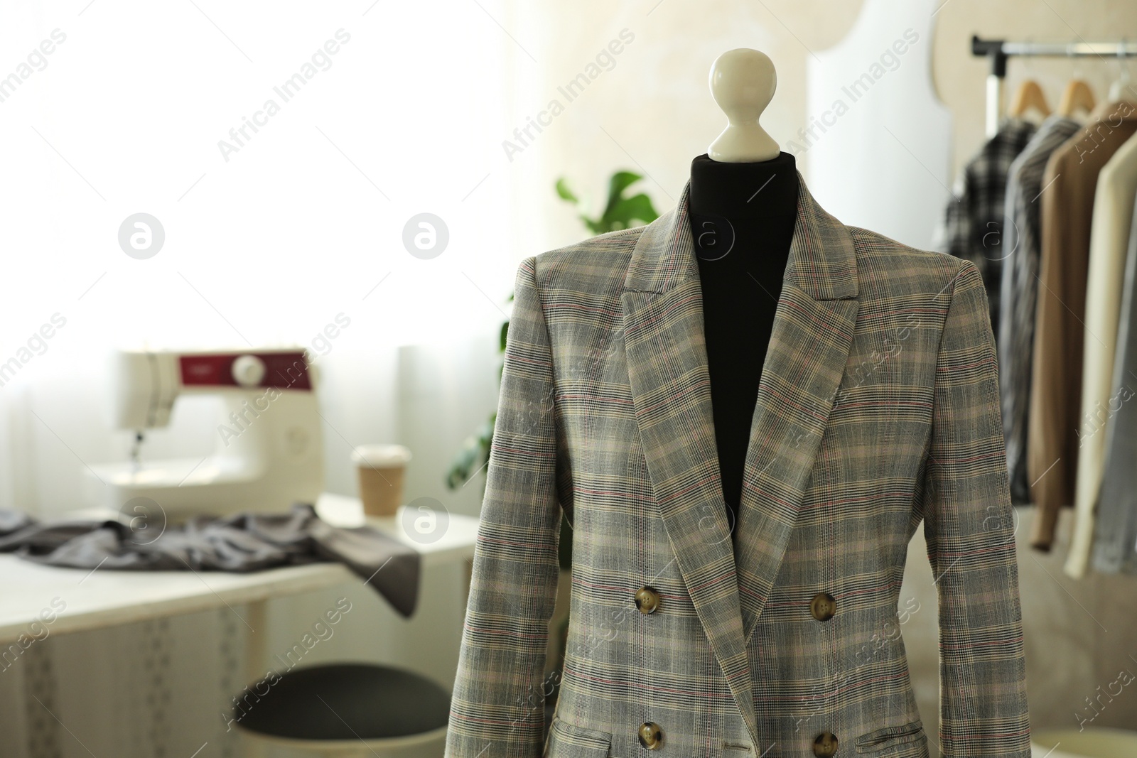 Photo of Mannequin with stylish jacket in tailor shop, space for text