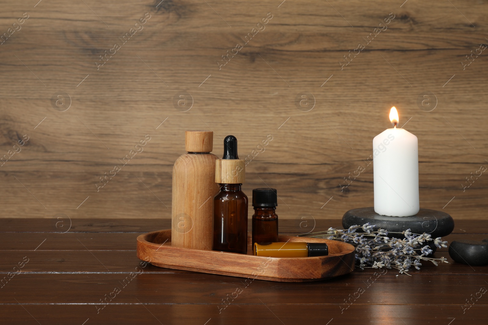 Photo of Aromatherapy products, burning candle and lavender on wooden table, space for text