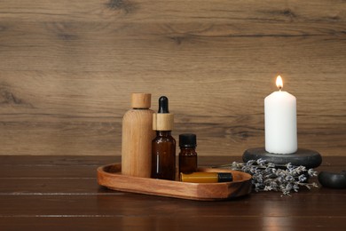Photo of Aromatherapy products, burning candle and lavender on wooden table, space for text