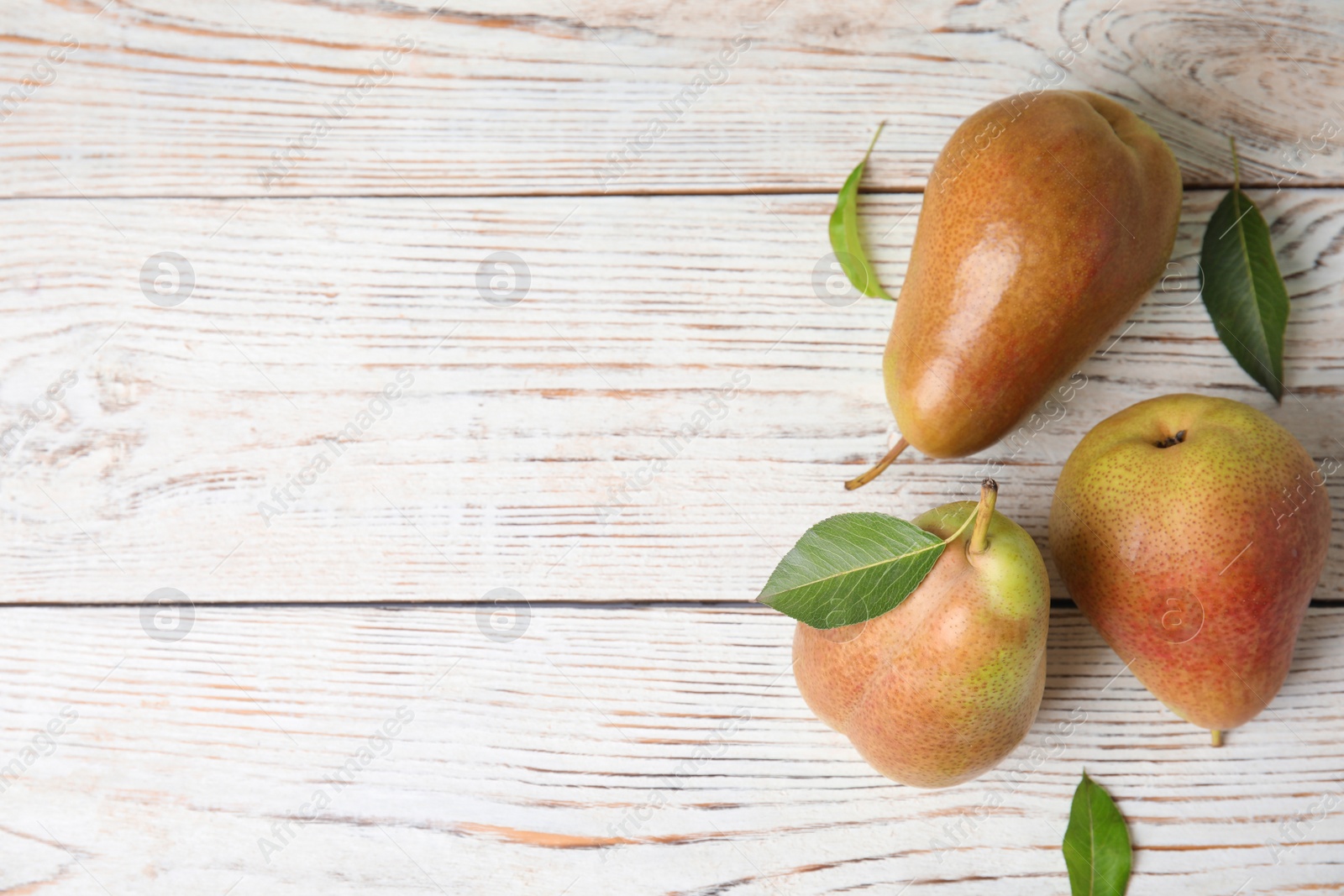 Photo of Ripe juicy pears on white wooden table, flat lay. Space for text