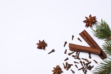 Different spices and fir branches on white table, flat lay. Space for text