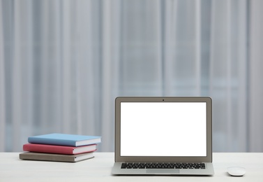 Laptop with blank screen on table indoors. Space for text