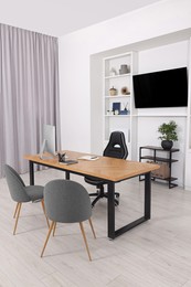Photo of Stylish director's workplace with wooden table, tv zone and comfortable armchairs in office. Interior design