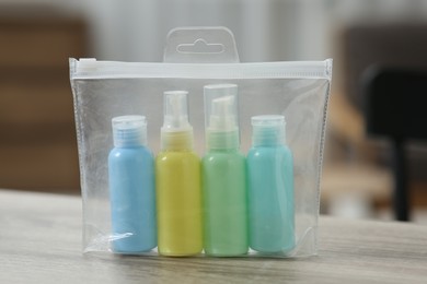 Cosmetic travel kit in plastic bag on wooden table, closeup. Bath accessories