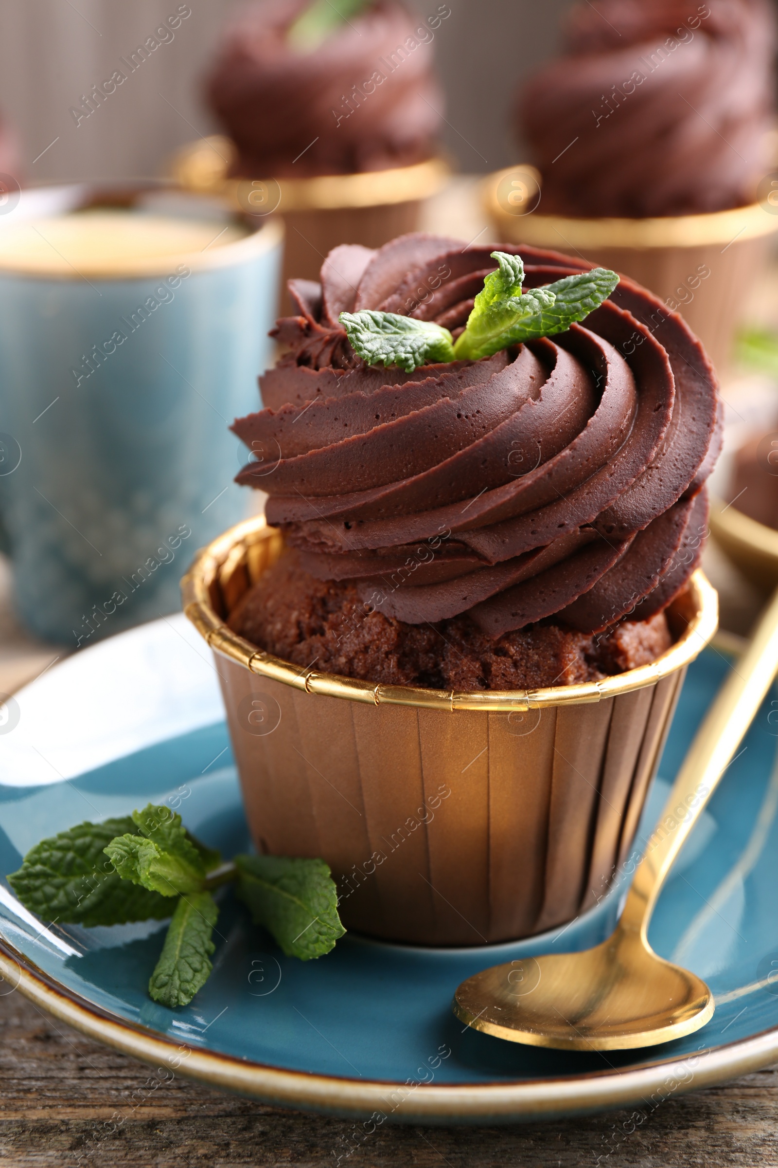 Photo of Delicious chocolate cupcake with mint on wooden table, closeup