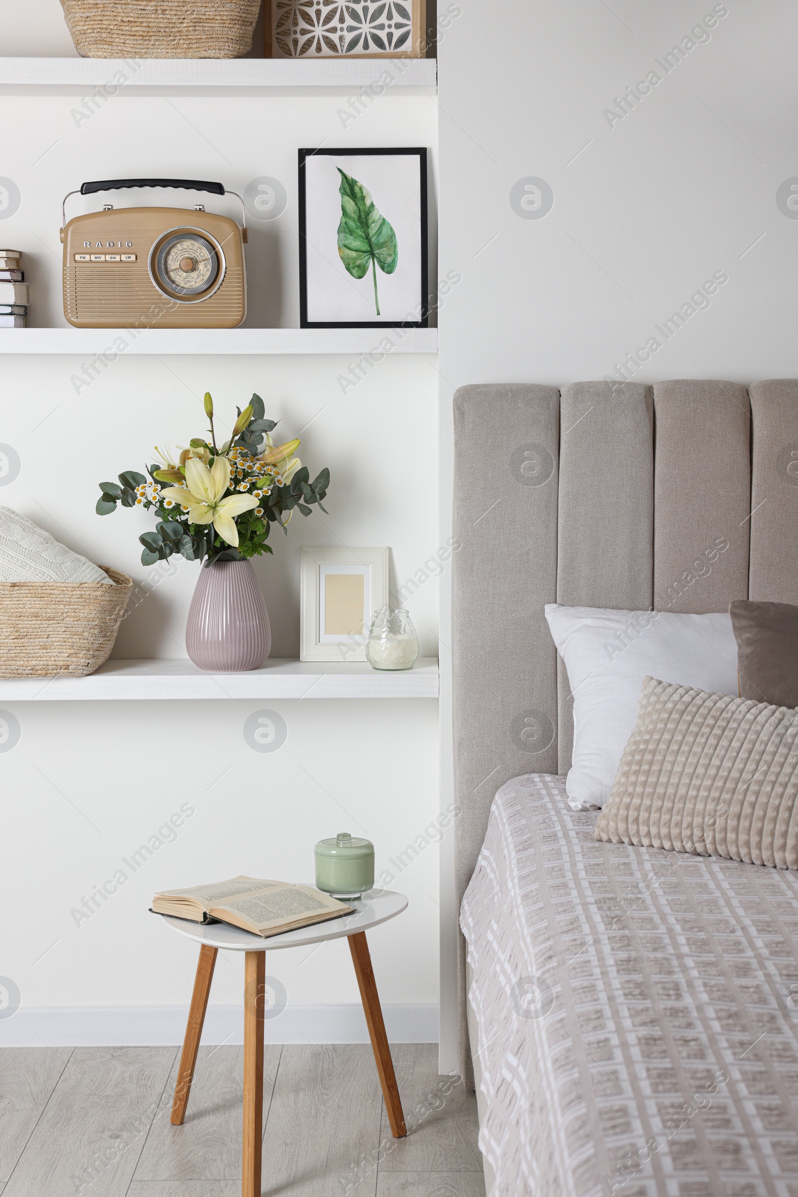 Photo of Stylish vase with flowers, retro radio and decor on shelves indoors. Bedroom interior elements
