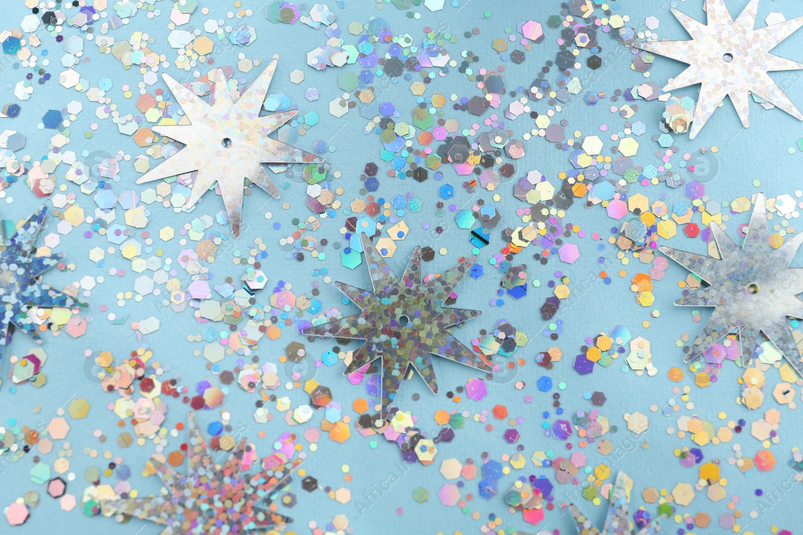 Photo of Shiny glitter on light blue background, above view