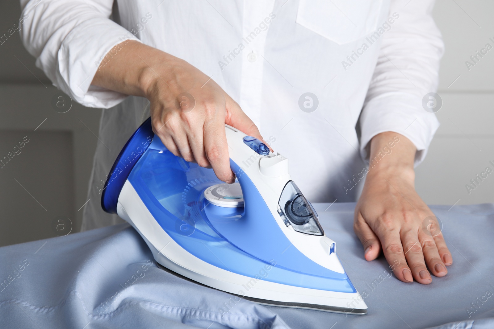 Photo of Woman ironing clean shirt on board, closeup