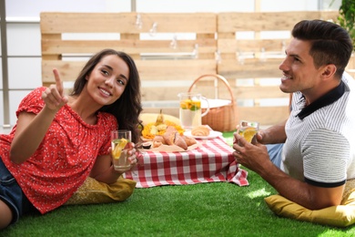 Happy couple with refreshing drinks imitating picnic at home