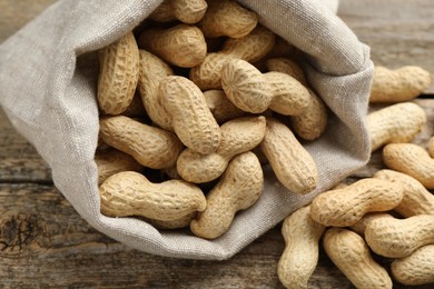 Fresh unpeeled peanuts in sack on wooden table