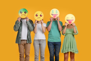 People covering faces with emoticons on yellow background