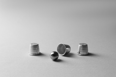 Photo of Metal thimbles and ball on light grey background. Thimblerig game