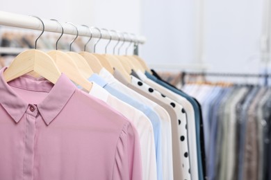 Photo of Dry-cleaning service. Many different clothes hanging on rack indoors, closeup