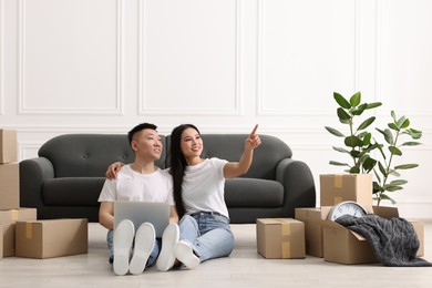 Happy couple with laptop on floor in their new apartment