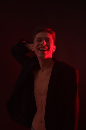 Photo of Sexy young man on dark background in neon lights