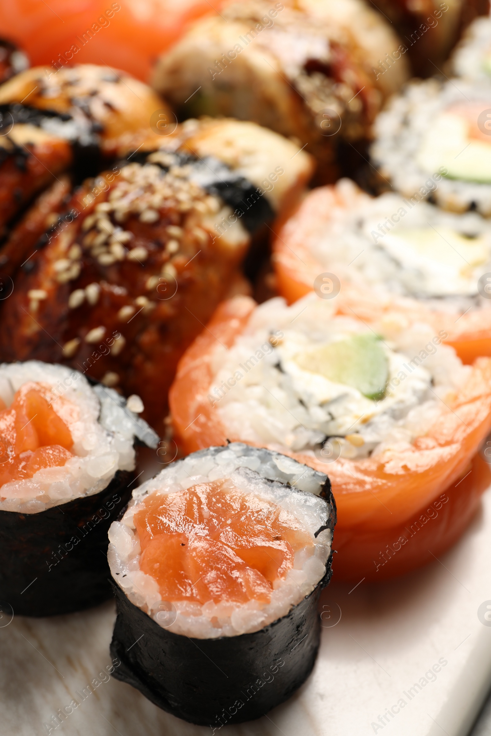 Photo of Different tasty sushi rolls on board, closeup