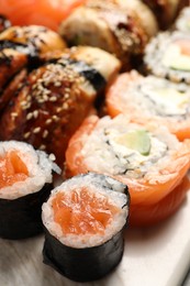 Different tasty sushi rolls on board, closeup