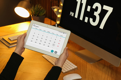 Woman using tablet with calendar app at workplace, closeup