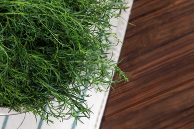 Photo of Colander with fresh tarragon leaves on wooden table, top view. Space for text