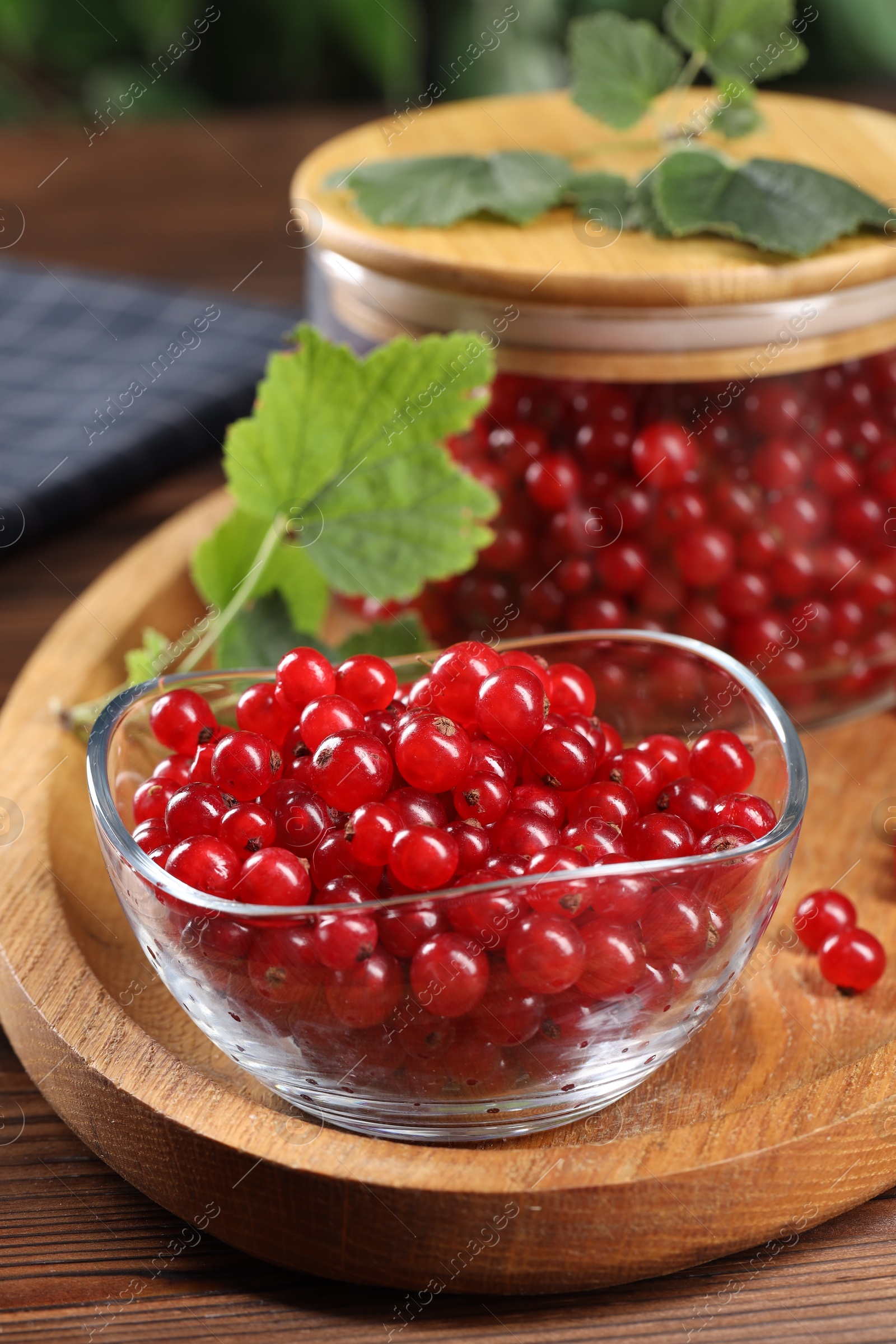 Photo of Ripe red currants and leaves on wooden table