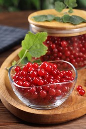 Photo of Ripe red currants and leaves on wooden table