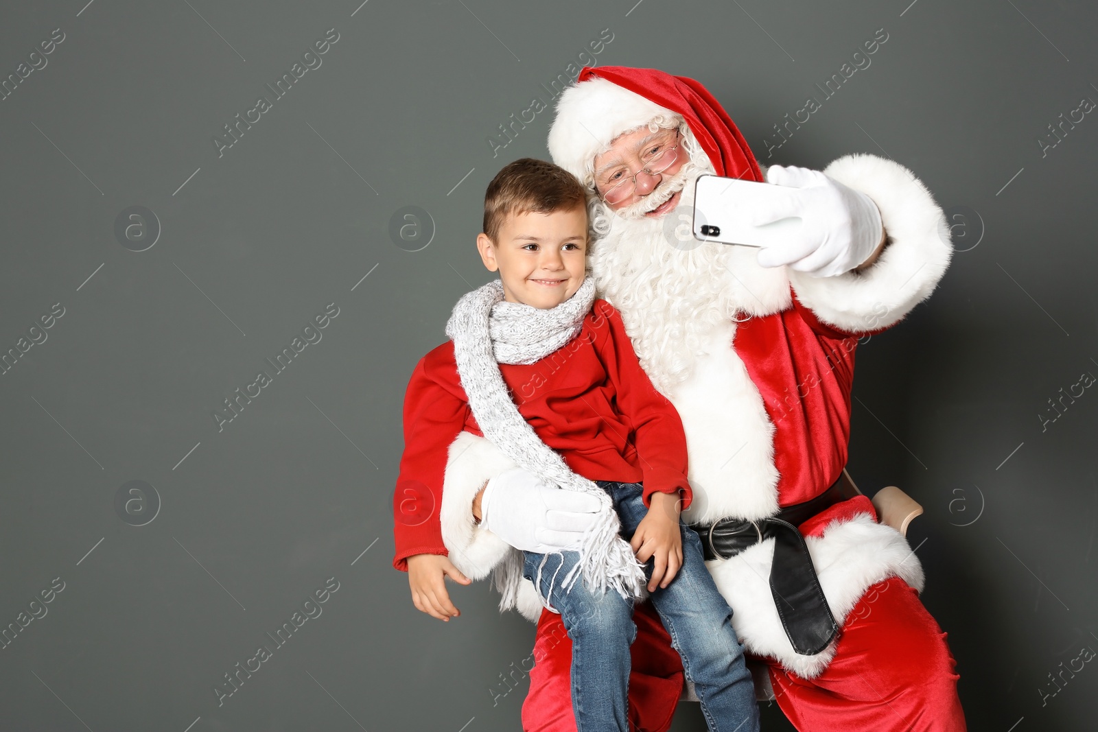 Photo of Authentic Santa Claus taking selfie with little boy on grey background