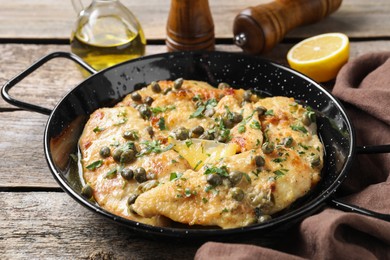 Photo of Delicious chicken piccata with herbs on wooden table