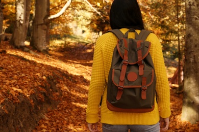 Woman with backpack walking in autumn forest. Space for text