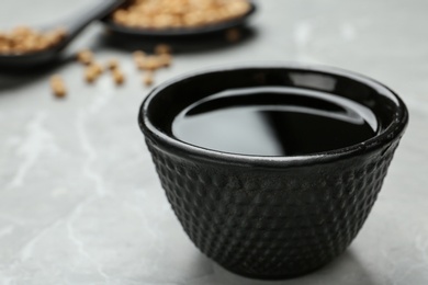 Bowl of soy sauce on grey table, closeup. Space for text