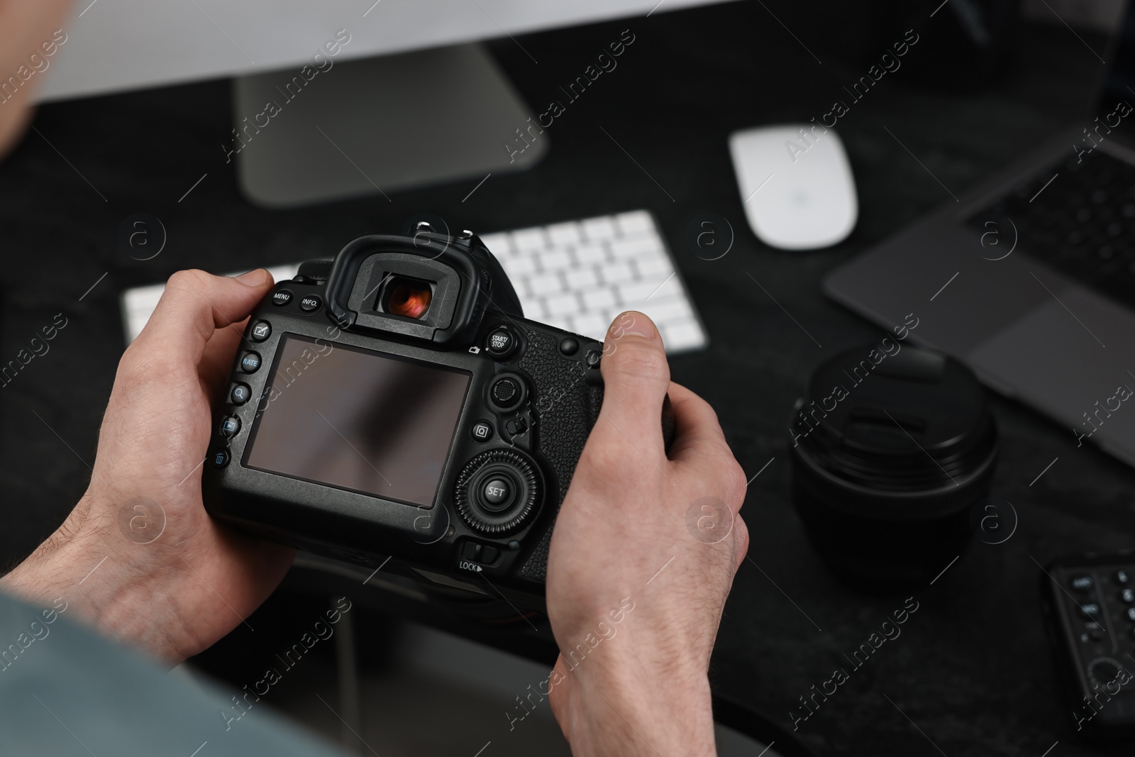 Photo of Photographer holding camera near dark table, closeup