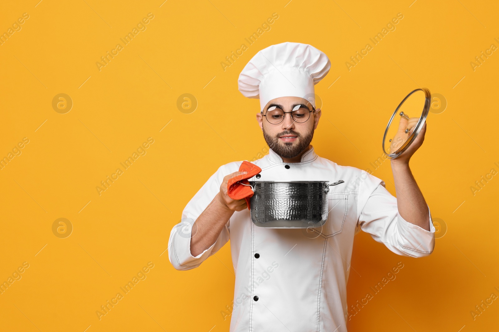 Photo of Professional chef smelling something in cooking pot on yellow background, space for text