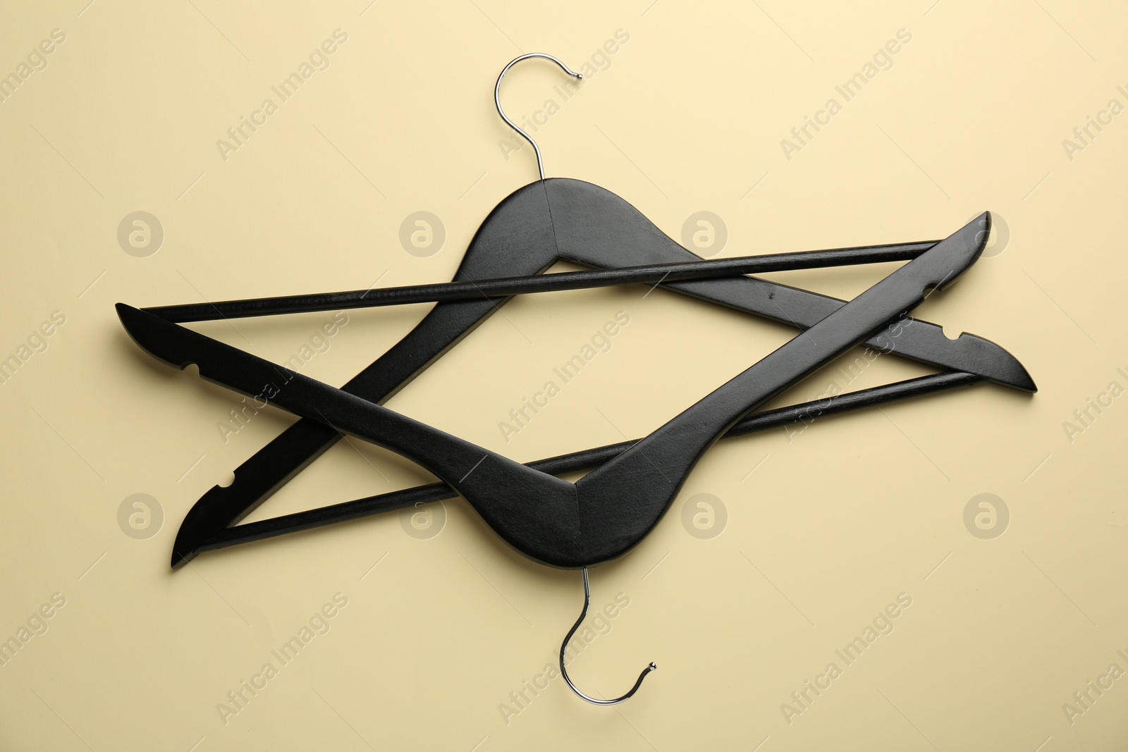Photo of Black hangers on pale yellow background, top view