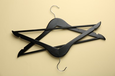 Black hangers on pale yellow background, top view