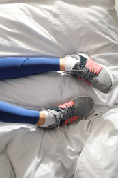 Photo of Lazy young woman sleeping on bed instead of morning training, top view