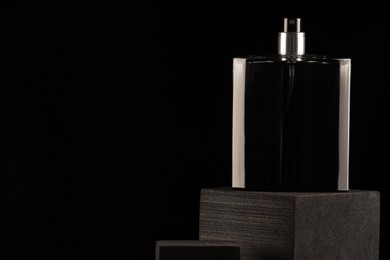 Photo of Luxury men`s perfume in bottle against black background, space for text