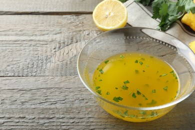 Photo of Bowl with lemon sauce and ingredients on wooden table, space for text. Delicious salad dressing