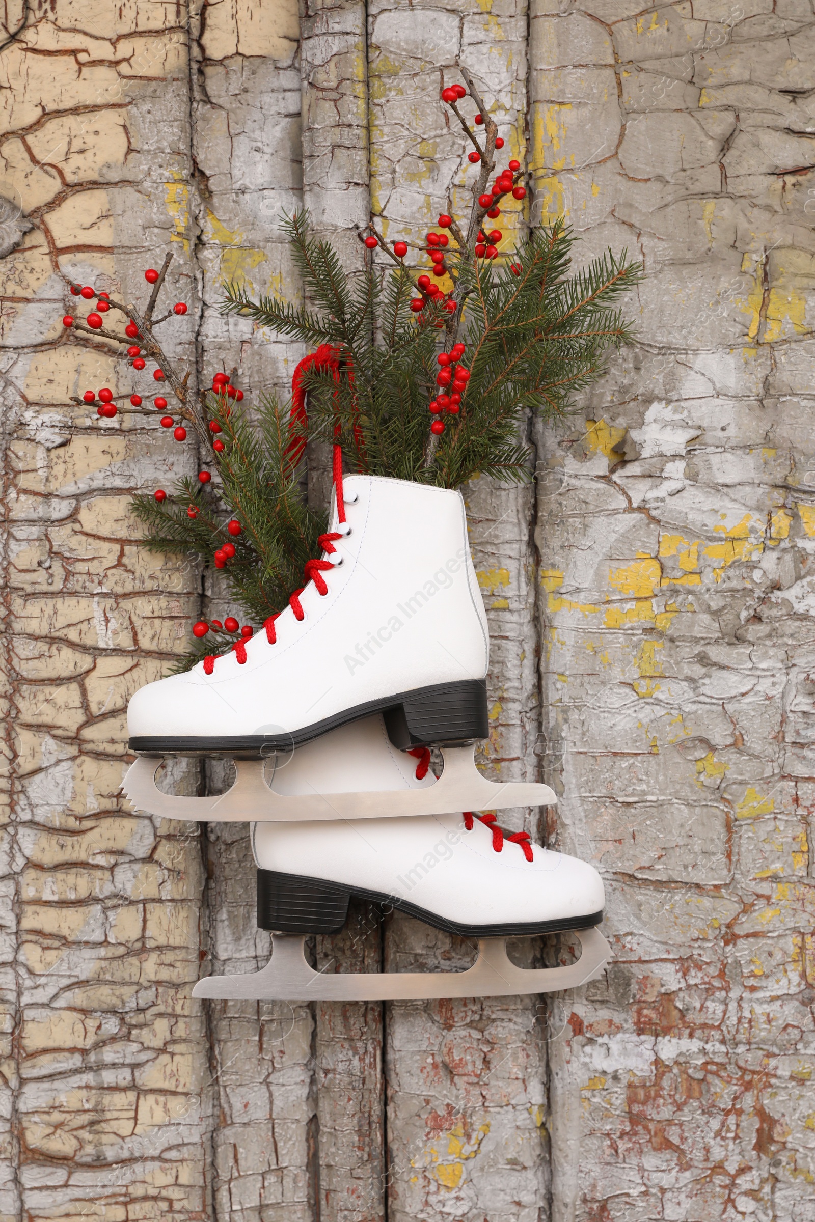 Photo of Pair of ice skates with Christmas decor hanging on old wooden door