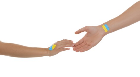 Photo of Man and woman with painted Ukrainian flags on their hands against white background, closeup