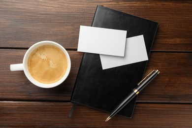 Blank business cards, coffee and notebook on wooden table, flat lay. Mockup for design