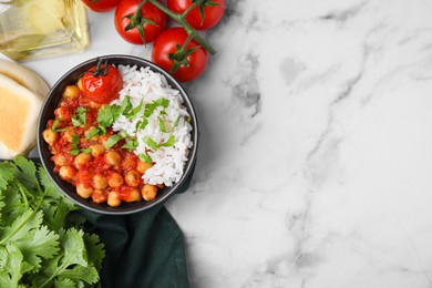 Photo of Delicious chickpea curry in bowl on white marble table, flat lay. Space for text