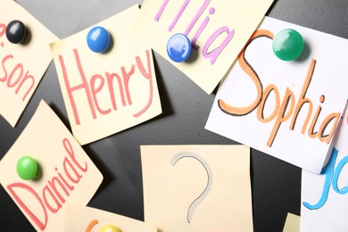 Photo of Notes with baby names on black board, closeup