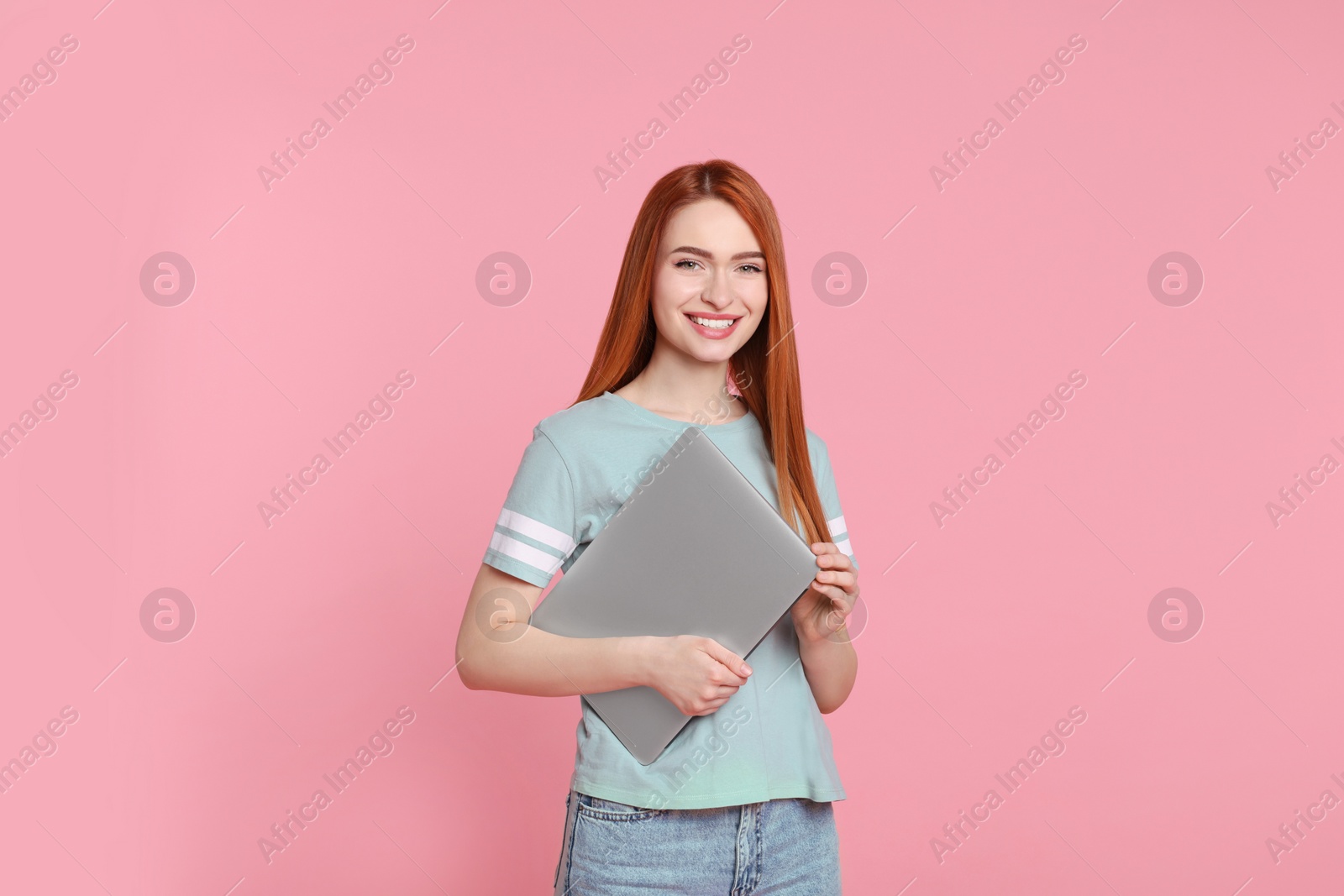 Photo of Smiling young woman with laptop on pink background